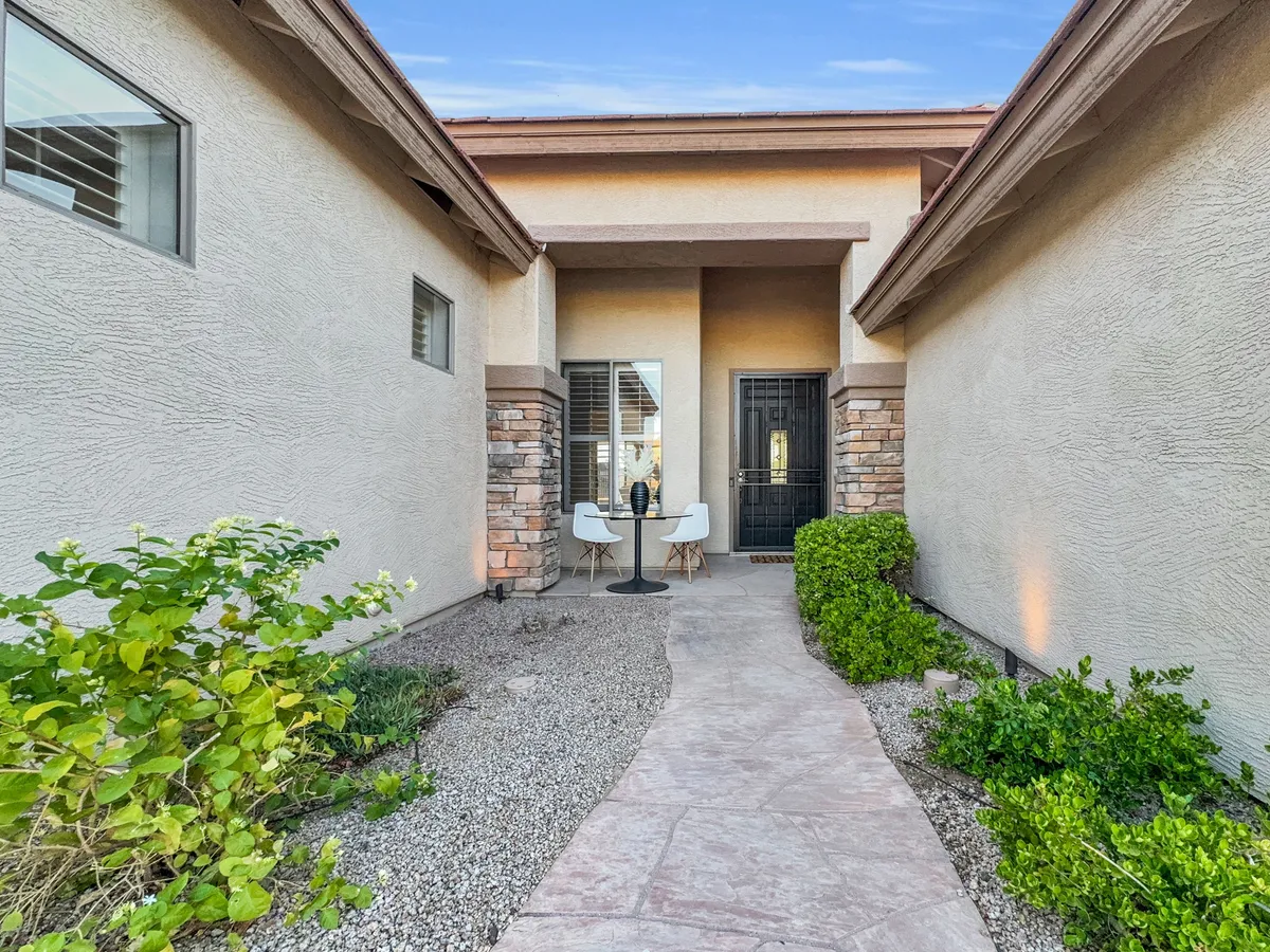 The charming front entrance features a landscaped path leading to the door, with a small table and chairs placed on the porch. This welcoming area hints at the broader community and the opportunity to step out for fresh air or a change of scenery while working remotely.