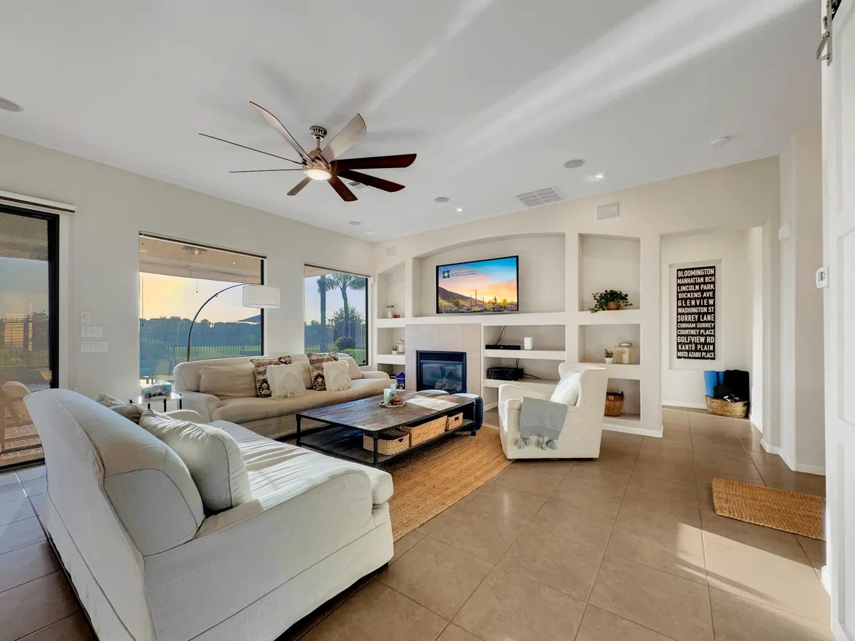 A cozy living area is shown here with a spacious couch, sleek modern coffee table, and a welcoming fireplace. Large windows frame an outdoor view, and the television is centrally placed for group movie or game nights.
