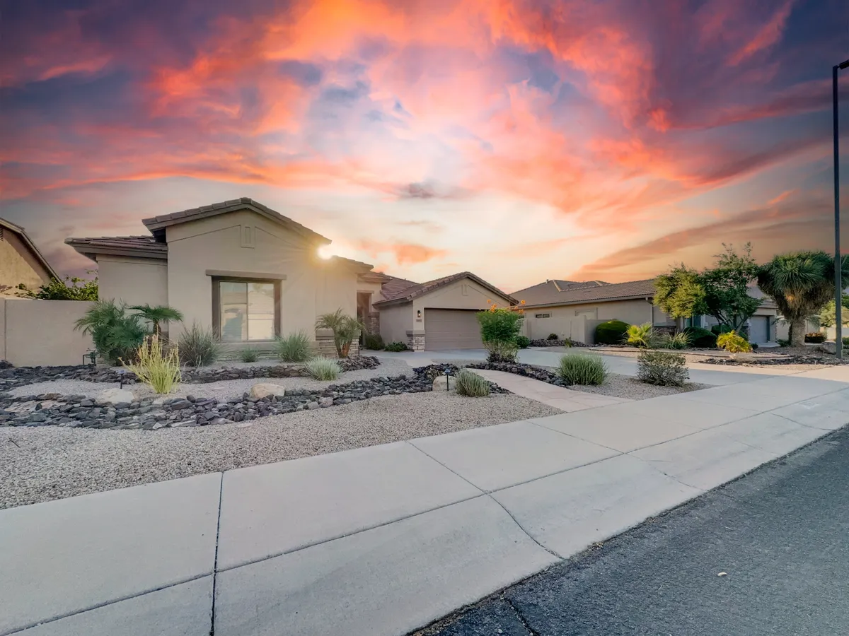 This exterior shot showcases the home's facade at dusk with a vibrant sky above and a landscaped yard in the foreground. The scene suggests tranquil evenings spent outdoors, whether gardening, hosting gatherings, or simply enjoying the peaceful surroundings.